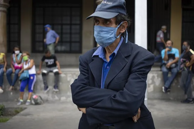 A man, wearing a protective face mask, waits for a bus in Caracas, Venezuela, Saturday, June 20, 2020, during a relaxation of restrictive measure to curb the spread of the new coronavirus. (Photo by Ariana Cubillos/AP Photo)
