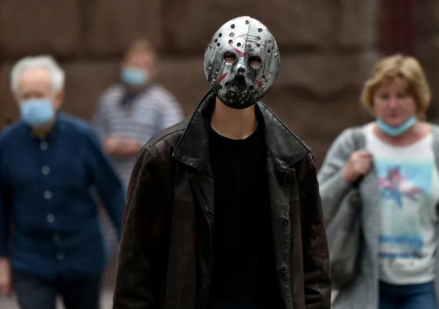 A man wearing an iron mask walks among people wearing surgical masks in the center of the Ukrainian capital of Kiev on July 13, 2020. (Photo by Sergei Supinsky/AFP Photo)