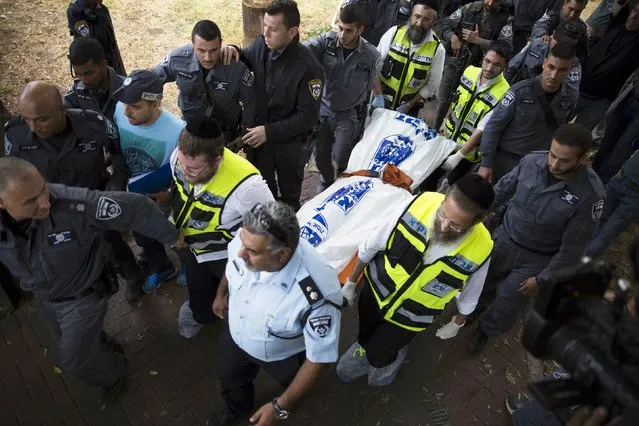 Israeli policemen accompany members of the Zaka Rescue and Recovery team as they remove the body of a suspected Palestinian militant in the southern town of Kiryat Gat, Israel October 7, 2015. (Photo by Amir Cohen/Reuters)