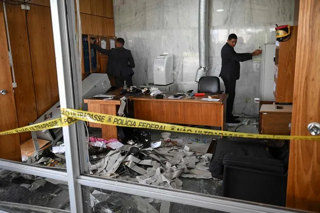 Planalto Presidential Palace security members inspect offices damaged by supporters of Brazilian former President Jair Bolsonaro after an invasion in Brasilia on January 9, 2023. Brazilian security forces locked down the area around Congress, the presidential palace and the Supreme Court Monday, a day after supporters of ex-president Jair Bolsonaro stormed the seat of power in riots that triggered an international outcry. In stunning scenes reminiscent of the Jan. 6, 2021 invasion of the US Capitol building by supporters of then-president Donald Trump, backers of Bolsonaro broke through police cordons and overran the seats of power in Brasilia, smashing windows and doors and ransacking offices. (Photo by Carl De Souza/AFP Photo)