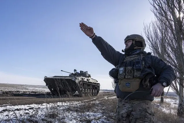 A Ukrainian commander of a unit aka Kurt shows a direction to an APC before shooting towards Russian positions at the frontline in Donetsk region, Ukraine, Monday, February 13, 2023. (Photo by Evgeniy Maloletka/AP Photo)