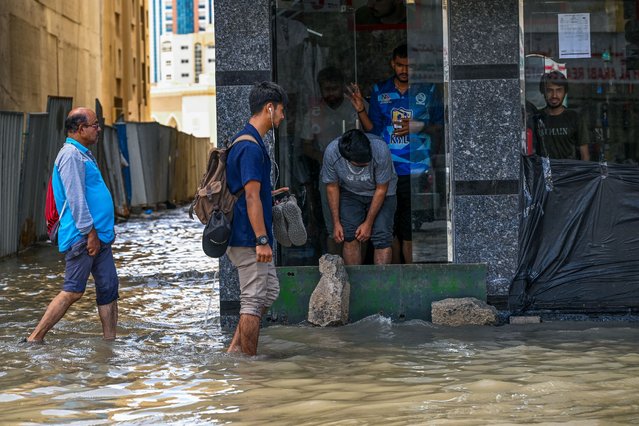 People wade through a flooded street following heavy rains in Sharjah on April 17, 2024. Dubai, the Middle East's financial centre, has been paralysed by the torrential rain that caused floods across the UAE and Bahrain and left 18 dead in Oman on April 14 and 15. (Photo by Ahmed Ramazan/AFP Photo)