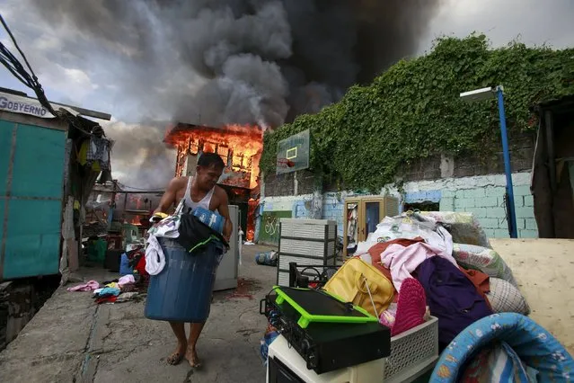 A resident saves their belongings while a fire razed residential area of Tambo town, Paranaque city, south of Manila October 29, 2015. At least some 50 houses made of light materials were destroyed by fire, affecting 150 families according to a Bureau of Fire Protection (BFP) official. (Photo by Romeo Ranoco/Reuters)