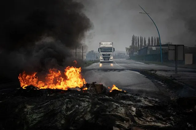 This photograph taken on March 8, 2023 shows a truck driving towards a fire during a blockade as part of the movement against the government's proposed pensions reform on the Radicatel Terminal of the harbour in Port Jerome sur Seine, near Rouen. Fuel deliveries and public transport were severely disrupted in France on March 7 as unions kicked off a fresh day of protest against a pensions reform that would push back the retirement age for millions. Unions have vowed to bring the country to a standstill with strikes over the proposed changes, which include raising the minimum retirement age to 64 from 62 and increasing the number of years people have to make contributions for a full pension. (Photo by Lou Benoist/AFP Photo)