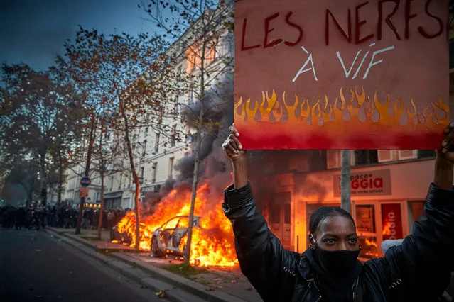 A protestor stands next to burning cars with a placard which reads “our blood is boiling” as thousands demonstrate against the French Government's Global Security Law on November 28, 2020 in Paris, France. France's lawmakers passed and adopted the bill known as article 24 of the “comprehensive security” law prohibiting the dissemination of images of the police, alarming journalists and activists saying civil liberties and press freedom could be compromised. Several MPs have criticised the bill's implications and President Macron has come under fire from national journalism unions and the UN for the law and police accountability. (Photo by Kiran Ridley/Getty Images)