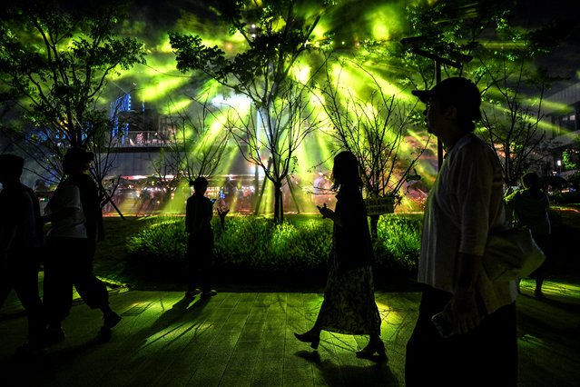 People walk under a light projection during the Shanghai International Light Festival at a shopping mall complex in Shanghai on September 22, 2025. (Photo by Jade Gao/AFP Photo)