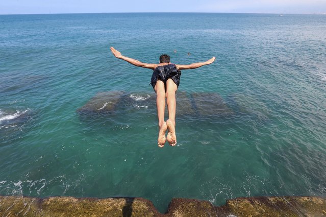 A youth jumps into the Mediterranean Sea, during a sunny day at the Corniche Al Manara in Beirut, Lebanon, 03 August 2025. (Photo by Wael Hamzeh/EPA)