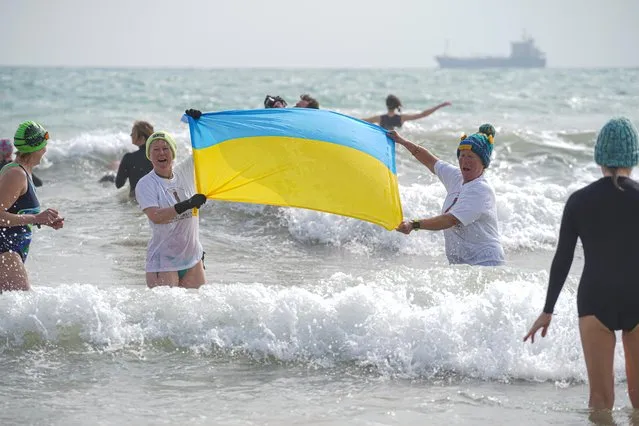 Swimmers display the Ukrainian flag as they take to the sea at Gyllyngvase Beach as over 200 local people join together to raise funds for the Red Cross to aid those affected by the war in the Ukraine on March 20, 2022 in Falmouth, England. (Photo by Hugh R. Hastings/Getty Images)