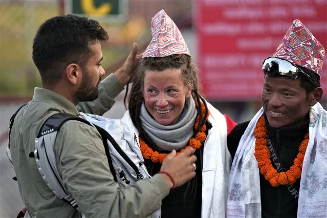 Norwegian climber Kristin Harila, 37, center, smiles as a man adjusts a traditional Nepalese cap presented to her after she arrived in Kathmandu, Nepal, Thursday, May 4, 2023. Harila who just became the fastest female climber to scale the 14 highest mountains in the world is now aiming to become the fastest person to complete the feat, beating a record set by a male climber in 2019. (Photo by Niranjan Shrestha/AP Photo)