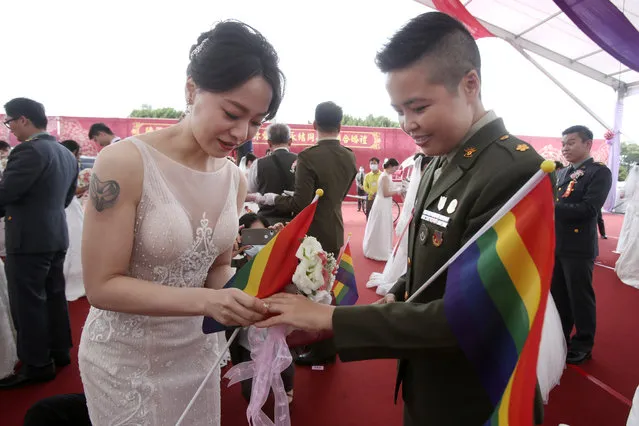 Lesbian couple Yumi Meng, left, puts a ring on Yi Wang' s finger during a military mass weddings ceremony in Taoyuan city, northern Taiwan, Friday, October 30, 2020. Two lesbian couples tied the knot in a mass ceremony held by Taiwan's military on Friday in a historic step for the island. Taiwan is the only place in Asia to have legalized gay marriage, passing legislation in this regard in May 2019. (Photo by Chiang Ying-ying/AP Photo)