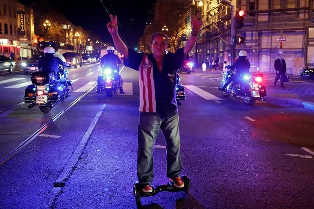 A man gestures as he rides a hoverboard near a group of police officers on motorcycles during a demonstration in San Francisco, California, U.S. following the election of Donald Trump as the president of the United States November 9, 2016. (Photo by Stephen Lam/Reuters)