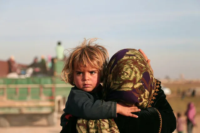 A woman carries a child as they return with others to the town of Hisha, after the Syrian Democratic Forces (SDF) took control of the area from Islamic State militants, in the northern Raqqa countryside, Syria November 14, 2016. (Photo by Rodi Said/Reuters)