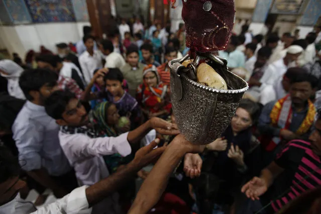 Devotees reach out for sacred water from a carved silver casing in the hallway at the tomb of Sufi saint Syed Usman Marwandi, also known as Lal Shahbaz Qalandar, in Sehwan Sharif, in Pakistan's southern Sindh province, September 5, 2013. (Photo by Akhtar Soomro/Reuters)