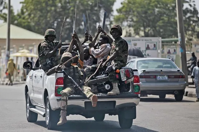 Soldiers and people carrying machetes ride on the back of a vehicle along a street in Gombe January 30, 2015. (Photo by Afolabi Sotunde/Reuters)