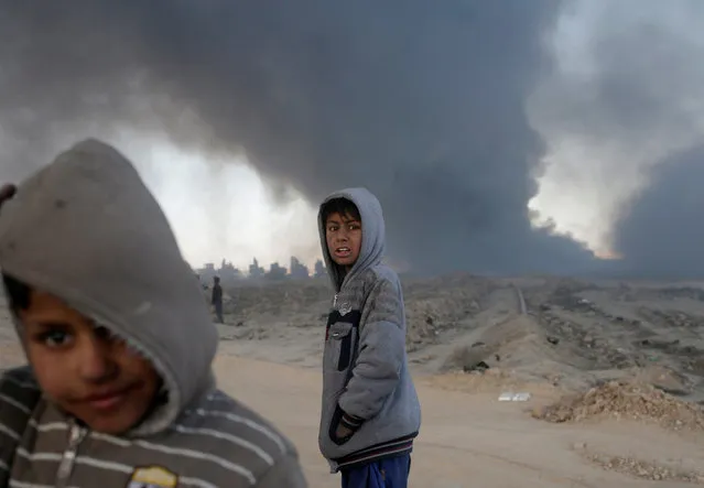 Boys stand in front of oilfields burned by Islamic State fighters in Qayyara, south of Mosul, Iraq November 23, 2016. (Photo by Goran Tomasevic/Reuters)