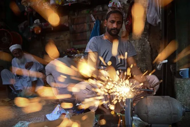 A blacksmith sharpens knives at a workshop ahead of the Muslim festival Eid al-Adha in Karachi on June 27, 2023. (Photo by Rizwan Tabassum/AFP Photo)