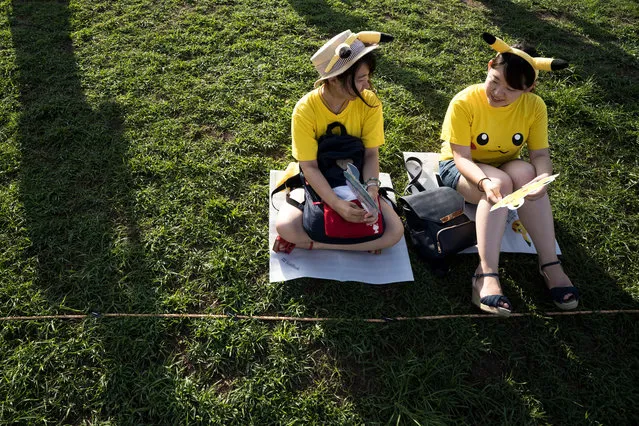 Women wait for performers dressed as Pikachu, a character from Pokemon series game titles, during the Pikachu Outbreak event hosted by The Pokemon Co. on August 10, 2018 in Yokohama, Kanagawa, Japan. (Photo by Tomohiro Ohsumi/Getty Images)