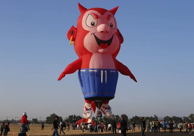 Spectators take pictures and watch the Burnie the Little Devil hot air balloon as it takes off during the Philippine International Hot Air Balloon Fiesta at Clark Freeport Zone in Pampanga province, north of Manila February 12, 2015. (Photo by Erik De Castro/Reuters)