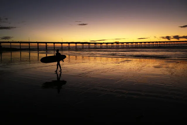 In this November 7, 2017 file photo a surfer walks out of the surf as the sun sets behind Ocean Beach pier in San Diego. California Gov. Jerry Brown announced Monday, August 20, 2018 that he signed a bill making surfing the official state sport. (Photo by Gregory Bull/AP Photo)