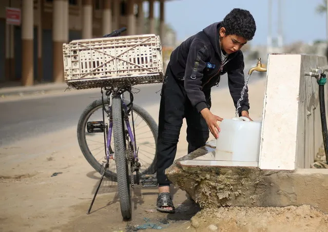 A Palestinian boy fills a container with water from a public tap On World Water Day, a United Nations observance day, in the southern Gaza Strip on March 22, 2021. (Photo by Ibraheem Abu Mustafa/Reuters)
