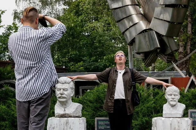A man poses for a picture with marble busts of Soviet leader Josef Stalin and Soviet state founder Vladimir Lenin in a park in Moscow, Russia on August 8, 2023. (Photo by Maxim Shemetov/Reuters)