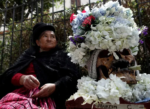 A woman sits by a skull at the General Cemetery during the Day of Skulls celebrations in La Paz, Bolivia on November 8, 2018. (Photo by David Mercado/Reuters)