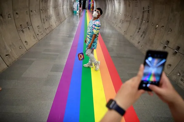 LGBT couple take photos of each other on a rainbow flag-themed path during pride month at Samyan MRT station in Bangkok, Thailand on June 4, 2021. (Photo by Soe Zeya Tun/Reuters)