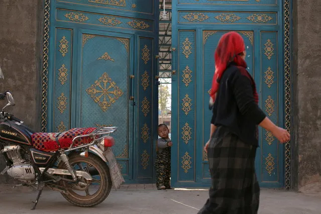 A child looks out from a door as a Uighur woman walks by in a residential area in Turpan, Xinjiang Uighur Autonomous Region on October 31, 2013. (Photo by Michael Martina/Reuters/File Photo)