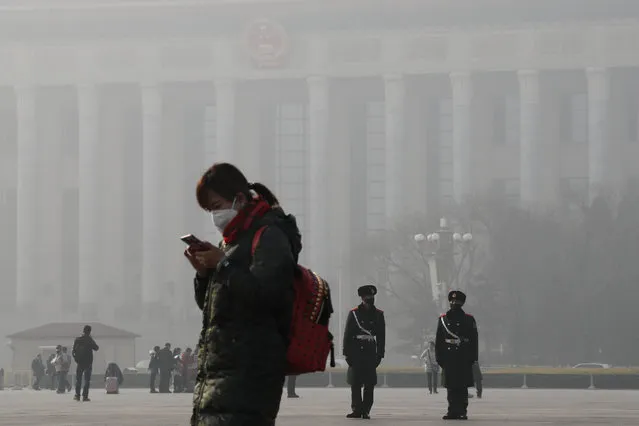 A woman walks past Chinese paramilitary policemen wearing protection masks on Tiananmen Square in Beijing as the capital of China is blanketed by heavy smog on Wednesday, January 4, 2017. China has long faced some of the worst air pollution in the world, blamed on its reliance of coal for energy and factory production, as well as a surplus of older, less efficient cars on its roads. Inadequate controls on industry and lax enforcement of standards have worsened the pollution problem. (Photo by Andy Wong/AP Photo)