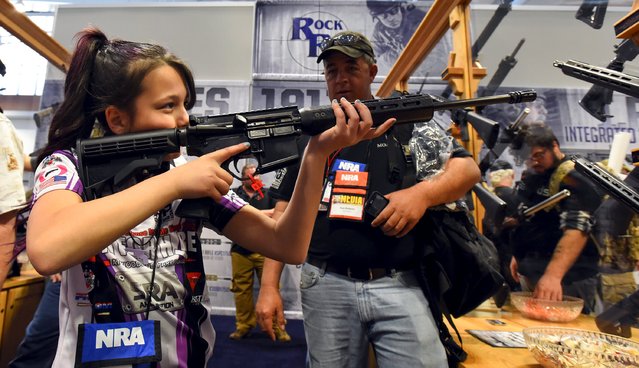 Shayanne Roberts looks at rifles in the trade booth area during the National Rifle Association's annual meeting in Nashville, Tennessee April 11, 2015. (Photo by Harrison McClary/Reuters)