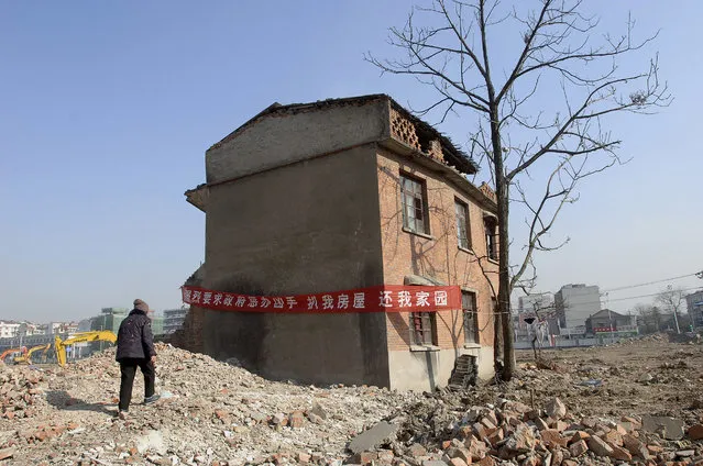A “nail house”, the last house in the area, is pictured at a construction site which will be developed into a new apartment zone in Hefei, Anhui province, China, January 3, 2008. The banner reads “strongly requesting the government to punish the developer who demolished my house, give back my home”. (Photo by Jianan Yu/Reuters)