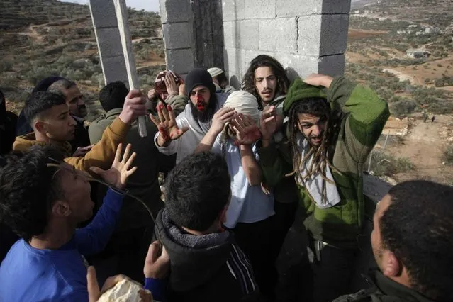 Palestinians hit Israeli settlers who are later detained by Palestinian villagers in a building under construction near the West Bank village of Qusra, southeast of the city of Nablus, Tuesday, January 7, 2014. (Photo by Nasser Ishtayeh/AP Photo)