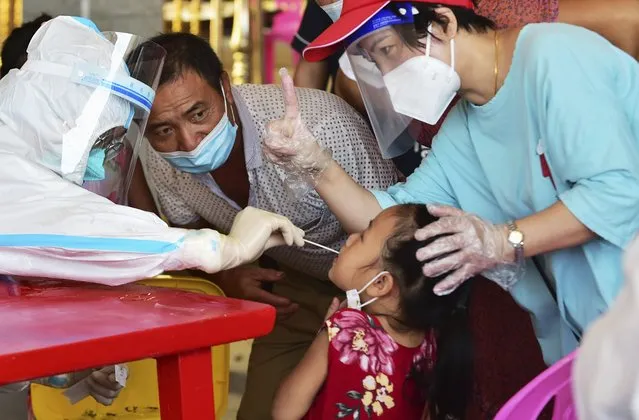 In this photo released by Xinhua News Agency, a health worker collects swab sample from a girl for nucleic acid testing in Xianyou county, Putian city, southeastern China's Fujian Province Thursday, September 16, 2021. China has reported another 62 cases of COVID-19, even as the number of Chinese citizens fully vaccinated has topped 1 billion. (Photo by Wei Peiquan/Xinhua via AP Photo)