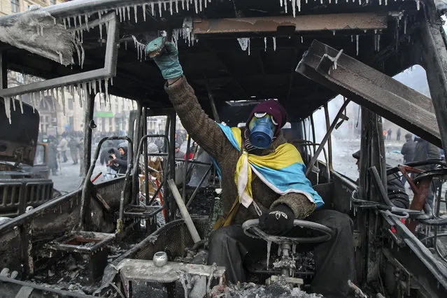 A protester sits in a burned police bus in Kiev, on January 20, 2014. (Photo by Valentyn Ogirenko/Reuters)