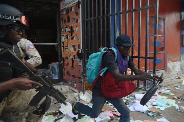 Haitian Police try to arrest a man who was caught looting a shop in the centre of Haitian Capital Port-au-Prince on February 12, 2019, as a sixth day of protests against Haitian President Jovenel Moise and the misuse of Petrocaribe funds continued. (Photo by Héctor Retamal/AFP Photo)