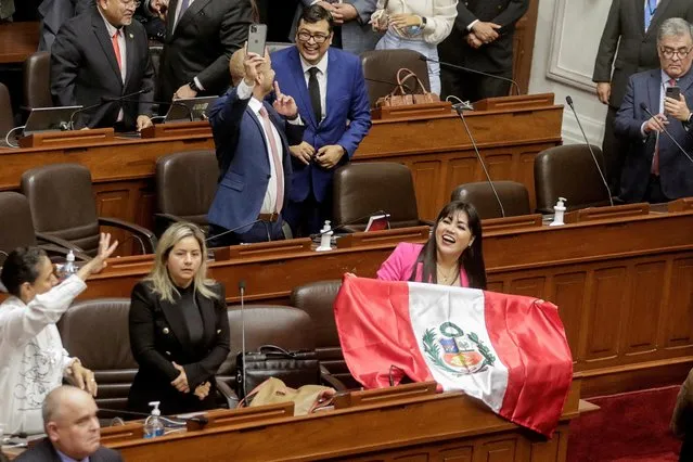 A member of Peru's Congress displays a Peruvian flag after Congress approved the removal of President Pedro Castillo, in Lima, Peru on December 7, 2022. (Photo by Sebastian Castaneda/Reuters)
