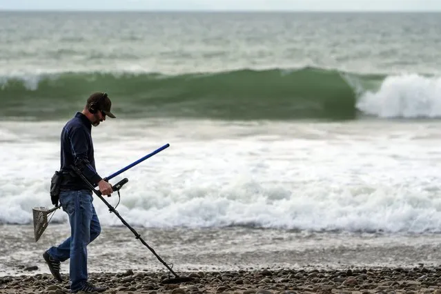 Josh Snider searches for metals with a metal detector on the edge of the beach ahead of storms, Wednesday, January 31, 2024, in Ventura, Calif. The first of two back-to-back atmospheric rivers slowly pushed into California on Wednesday, triggering statewide storm preparations and calls for people to get ready for potential flooding, heavy snow and damaging winds. (Photo by Damian Dovarganes/AP Photo)