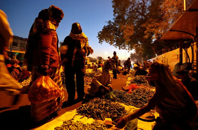 People buy vegetables from a roadside market in the early morning in Ahmedabad February 1, 2017. (Photo by Amit Dave/Reuters)