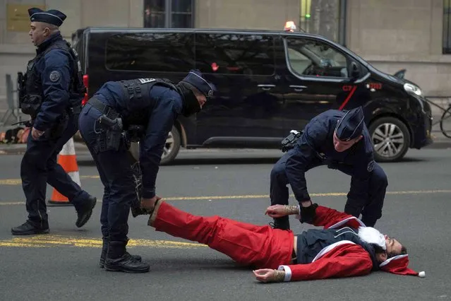 Police officers evacuate an activist dressed as Santa Claus outside the Ecological transition ministry in Paris, during an action by “Extinction Rebellion” to denounce the government's environmental policy on the eve of the start in Montreal of the COP15 biodiversity summit in Paris, on December 6, 2022. (Photo by Anna Kurth/AFP Photo)