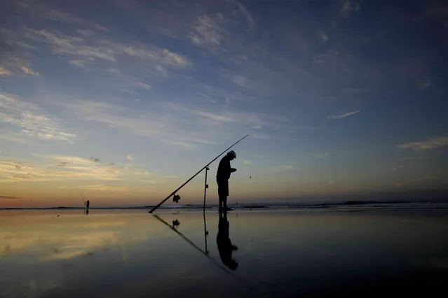 A fisherman prepares his rod on the shore of the South Atlantic Ocean in Monte Hermoso, Argentina, Wednesday, February 21, 2024. (Photo by Natacha Pisarenko/AP Photo)