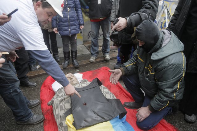 People look at a bullet hole in victim's vest who was killed during a  clash between riot police and protesters  in Kiev's Independence Square, the epicenter of the country's current unrest, Thursday, February 20, 2014. (Photo by Efrem Lukatsky/AP Photo)