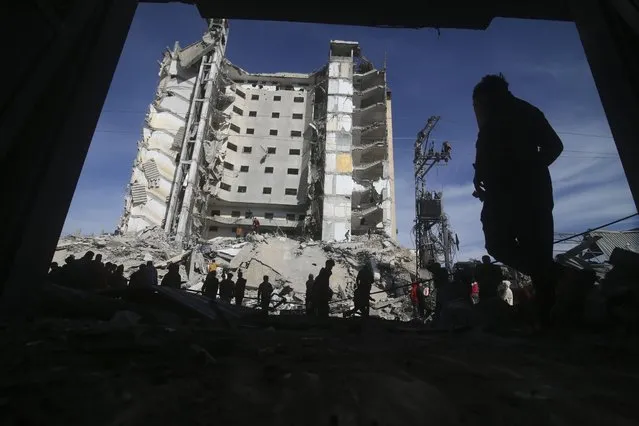 Palestinians walk by a residential building destroyed in an Israeli strike in Rafah, Gaza Strip, Saturday, March 9, 2024. (Photo by Hatem Ali/AP Photo)
