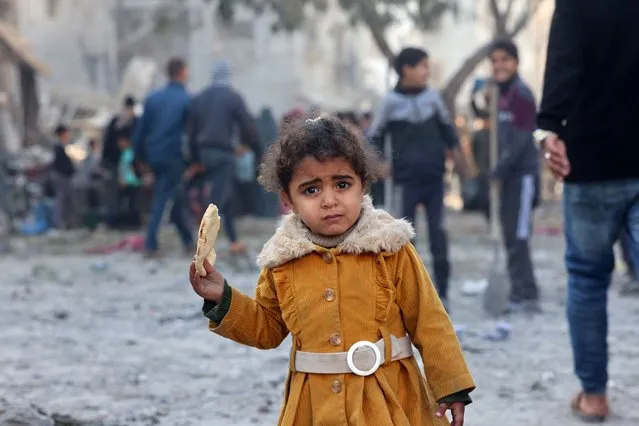 A Palestinian girl holds a piece of bread in Rafah refugee camp after Israeli strikes in Rafah, Gaza on February 19, 2024. (Photo by Mohammed Abed/AFP Photo)