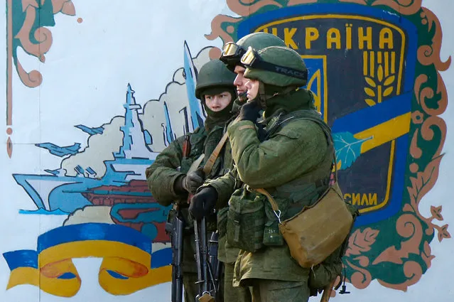Military personnel, believed to be Russian servicemen, stand guard outside the territory of a Ukrainian military unit in the village of Perevalnoye outside Simferopol March 3, 2014. Ukraine mobilised for war on Sunday and Washington threatened to isolate Russia economically after President Vladimir Putin declared he had the right to invade his neighbour in Moscow's biggest confrontation with the West since the Cold War. (Photo by David Mdzinarishvili/Reuters)