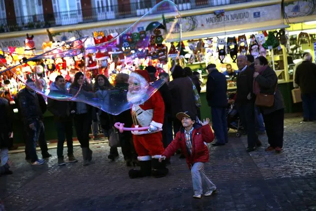 A boy chases a giant soap bubble at Plaza Mayor square's Christmas market in downtown Madrid December 10, 2014. (Photo by Susana Vera/Reuters)