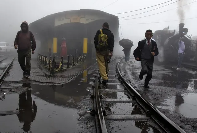 People cross tracks as a Darjeeling Himalayan Railway train, which runs on a 2 foot gauge railway and is a UNESCO World Heritage Site, prepares to depart from a station in Ghum, India, June 25, 2019. (Photo by Ranita Roy/Reuters)