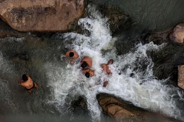 Hindu devotees take a dip into a stream in the waters of river Narmada on the occasion of Makar Sankranti a day considered to be of great religious significance in Hindu mythology at Budhni about 60 kms from Bhopal on January 14, 2022. (Photo by Gagan Nayar/AFP Photo)