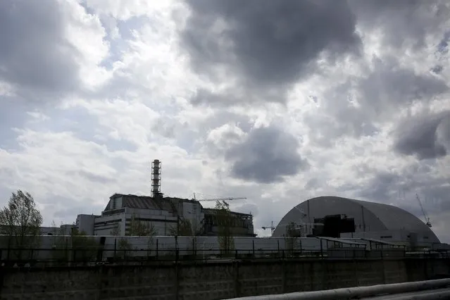 A general view shows a containment shelter for the damaged fourth reactor (L) and the New Safe Confinement (NSC) structure (R) at the Chernobyl Nuclear Power Plant, Ukraine April 22, 2016. Picture taken through a bus window. (Photo by Gleb Garanich/Reuters)