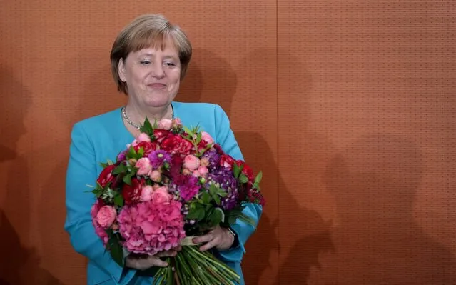 German Chancellor Angela Merkel holds a bunch of flowers that she received as a birthday present prior to the weekly cabinet meeting at the Chancellery in Berlin, Germany, Wednesday, July 17, 2019. Merkel is today 65 years old. (Photo by Michael Sohn/AP Photo)