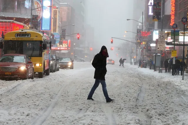 A commuter walks across a street during a snowstorm in Times Square in Manhattan, New York, U.S., March 14, 2017. (Photo by Carlo Allegri/Reuters)